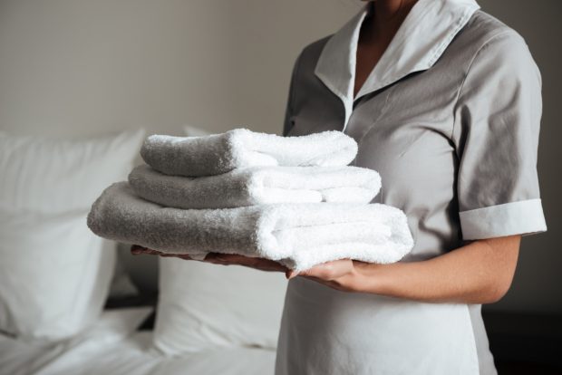 Pracownica hotelu trzymająca białe ręczniki