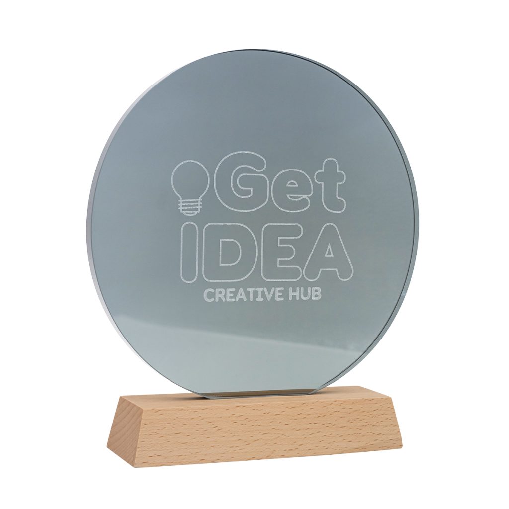 Okrągła statuetka z lustrzanego akrylu na drewnianej podstawce z grawerem logo Get Idea Creative Hub