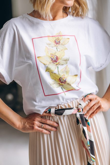 Kobieta w białym t-shircie z nadrukiem i beżowej spódniczce