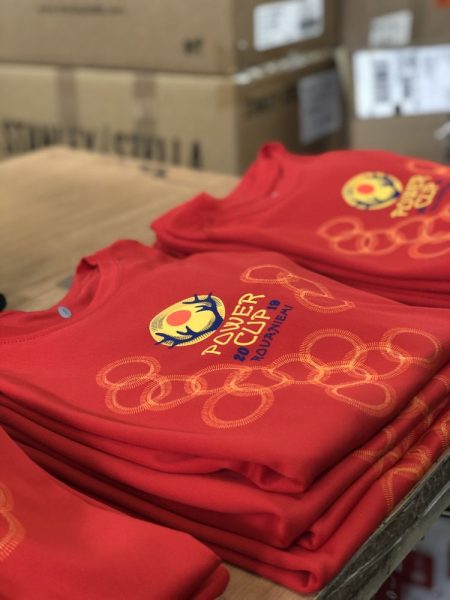 Stosy czerwonych t-shirtów z kolorowym nadrukiem na tle kartonów