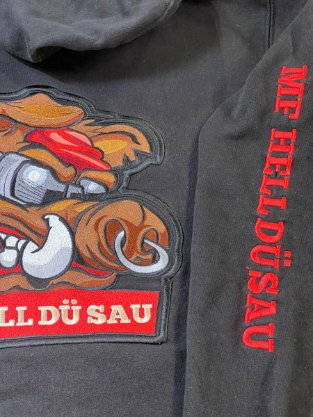 Zbliżenie haftu dzika i czerwonego napisu na czarnej bluzie