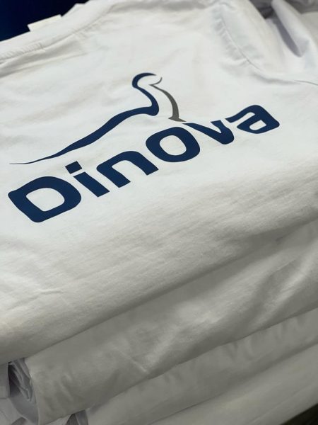 Stos białych koszulek z granatowym nadrukiem Dinova