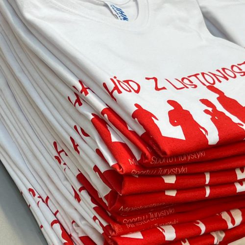 stos białych koszulek z czerwonym nadrukiem