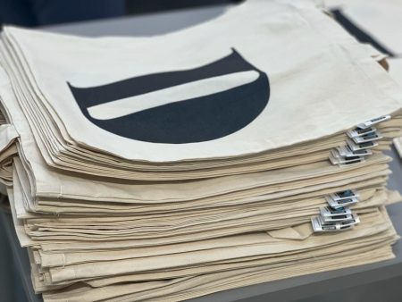 Stos bawełnianych toreb z metką i nadrukiem litery D