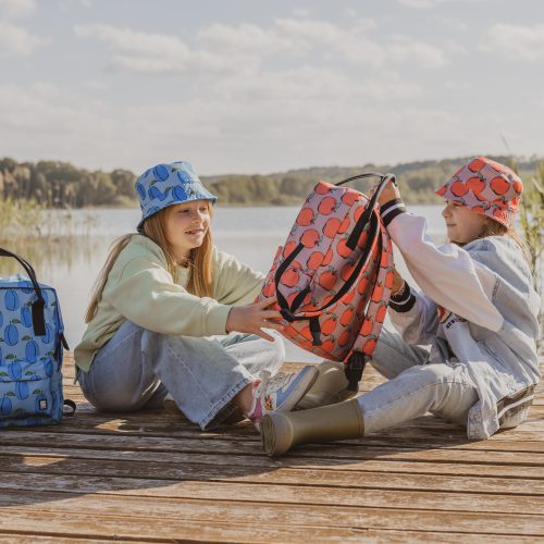 dwie dziewczynki siedzące na pomoście z plecaczkami